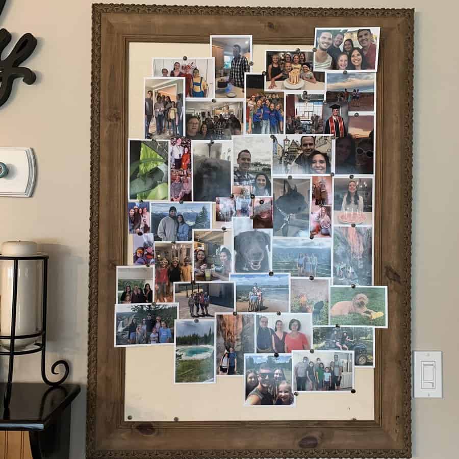 A bulletin board filled with various family and travel photos in a wooden frame, hung on a beige wall