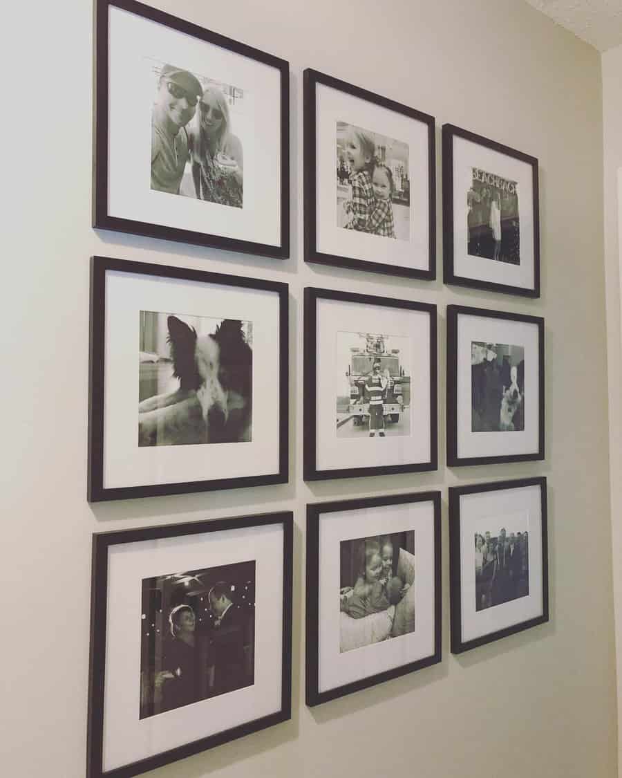 A 3x3 grid of black-framed, black-and-white photos on a wall, featuring people, a dog, and everyday scenes