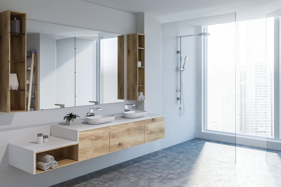 Modern bathroom with dual sinks, wooden cabinets, large mirror, and a walk-in shower, bright daylight through a big window