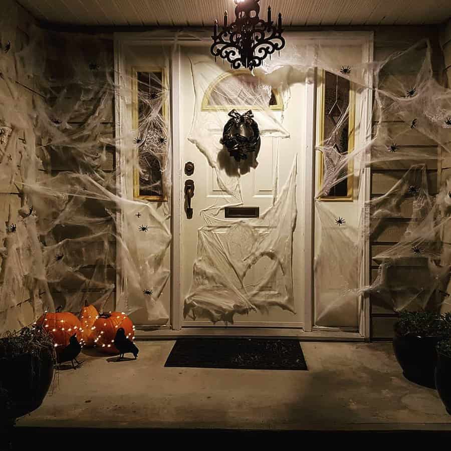 Front porch Halloween decorations with spider webs, pumpkins, and black birds