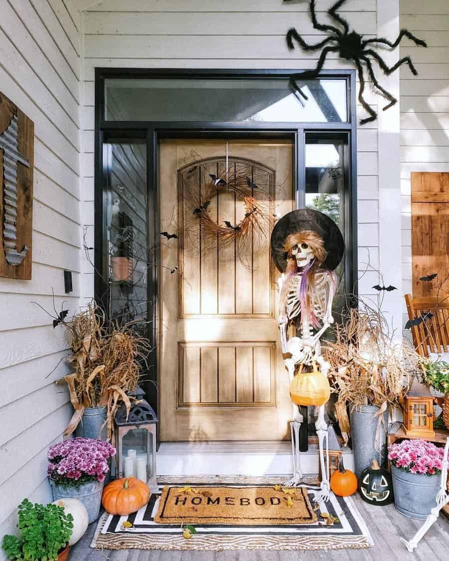 Halloween-decorated porch with skeleton, pumpkins, spider, and autumn wreath