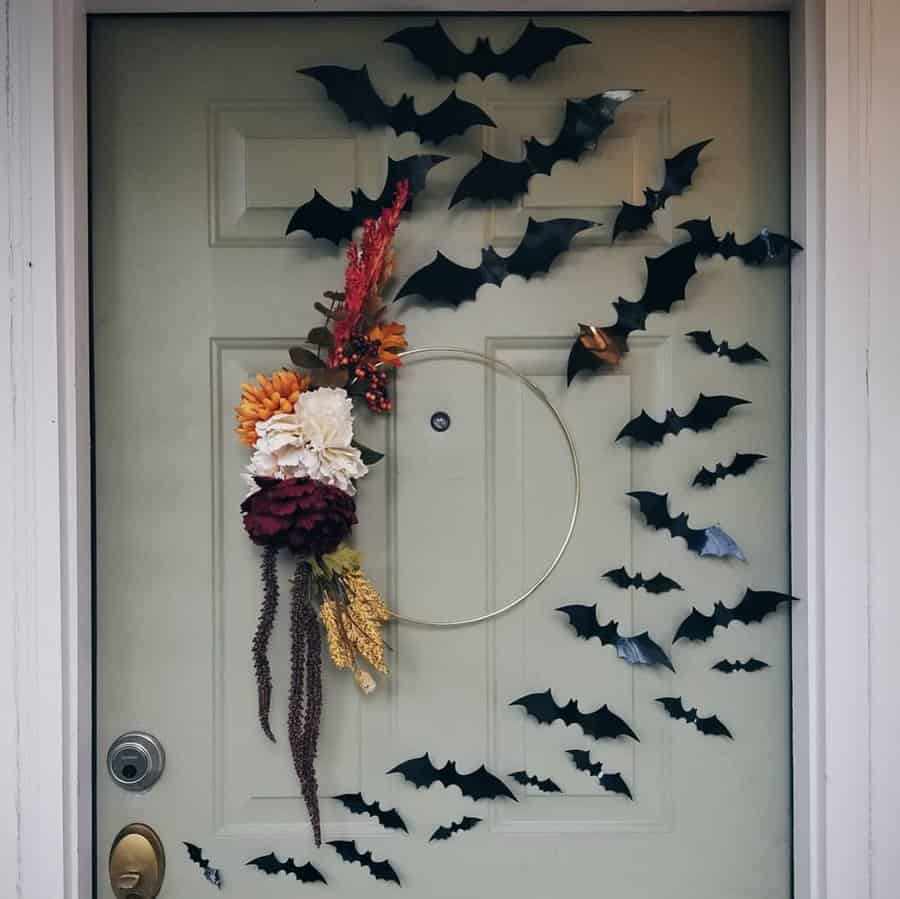 A door decorated with paper bats and a floral wreath for Halloween