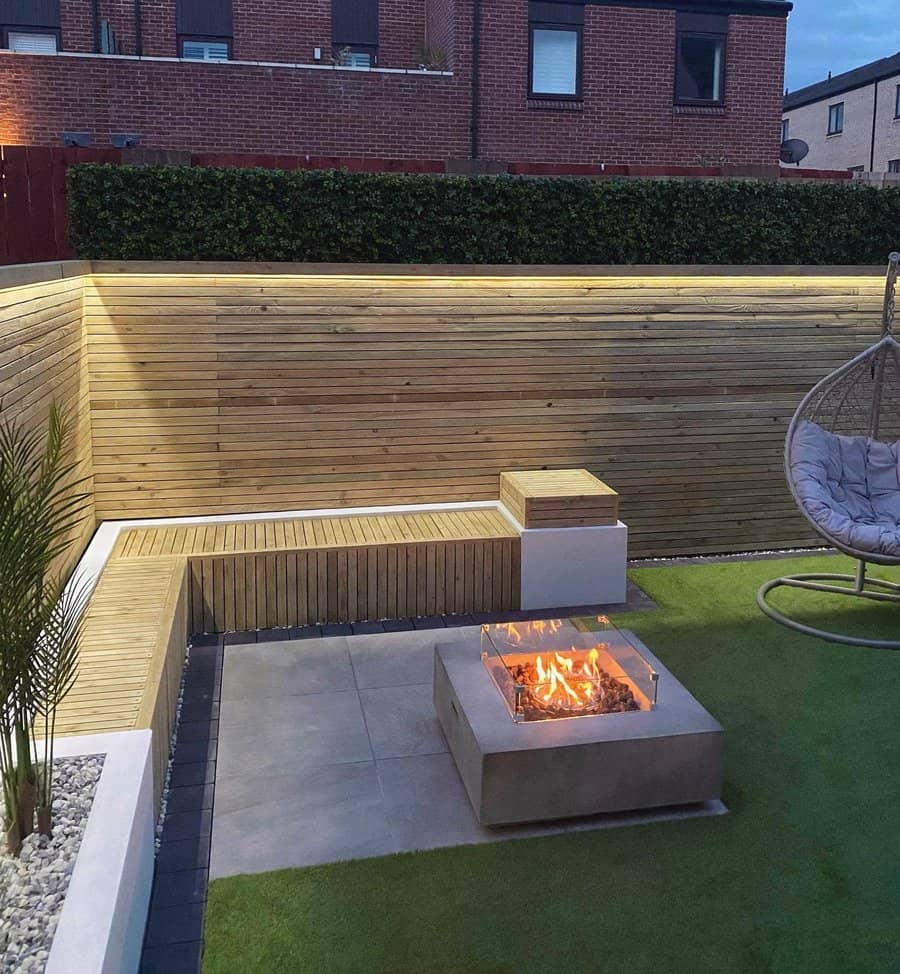 Backyard at dusk with lit horizontal fence and fire pit