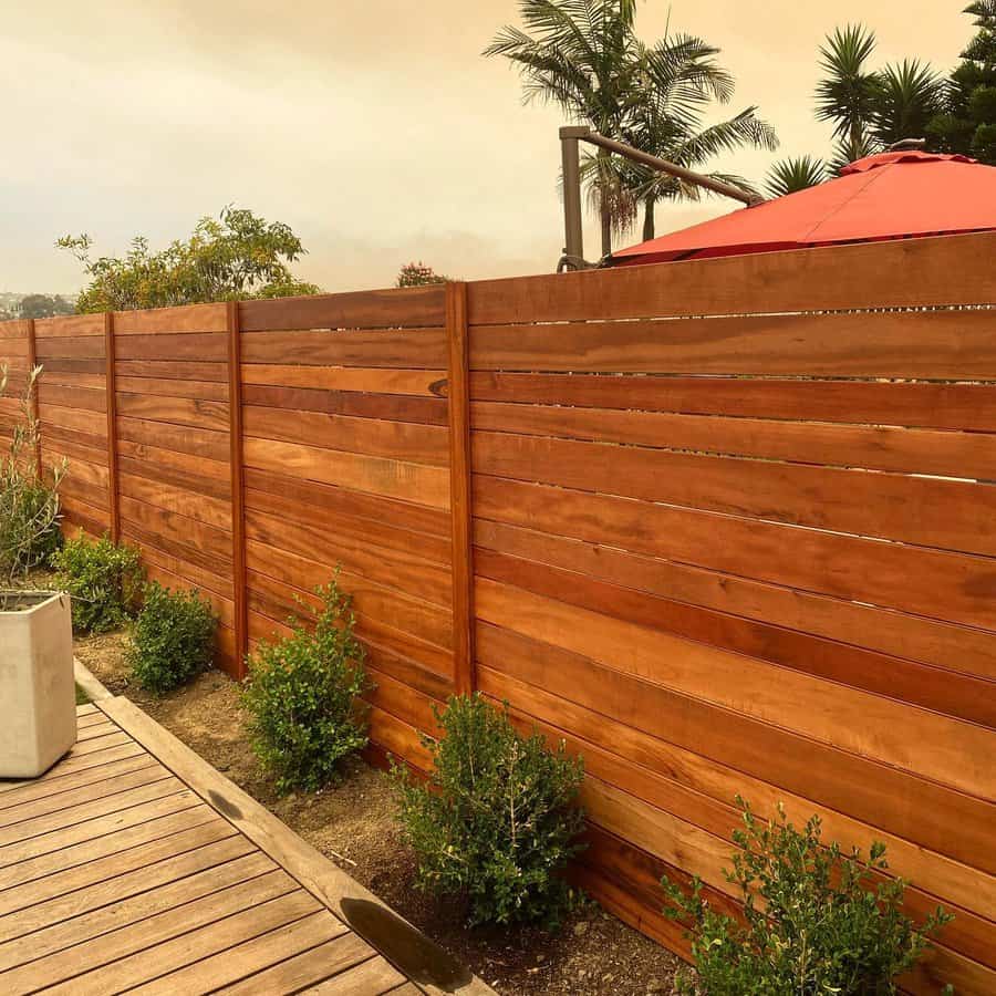 Stained wooden horizontal fence with shrubs