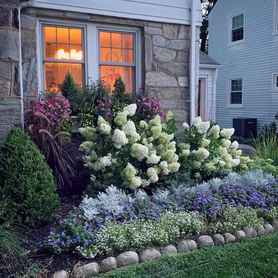 Charming front yard design with vibrant hydrangeas, colorful perennial flowers, and neatly trimmed shrubs, creating a cozy and inviting look