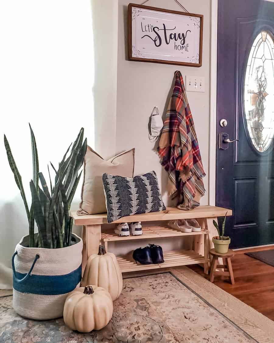 Cozy entryway with a wooden bench, fall decor, woven accents, and a welcoming sign, blending rustic charm with functional storage