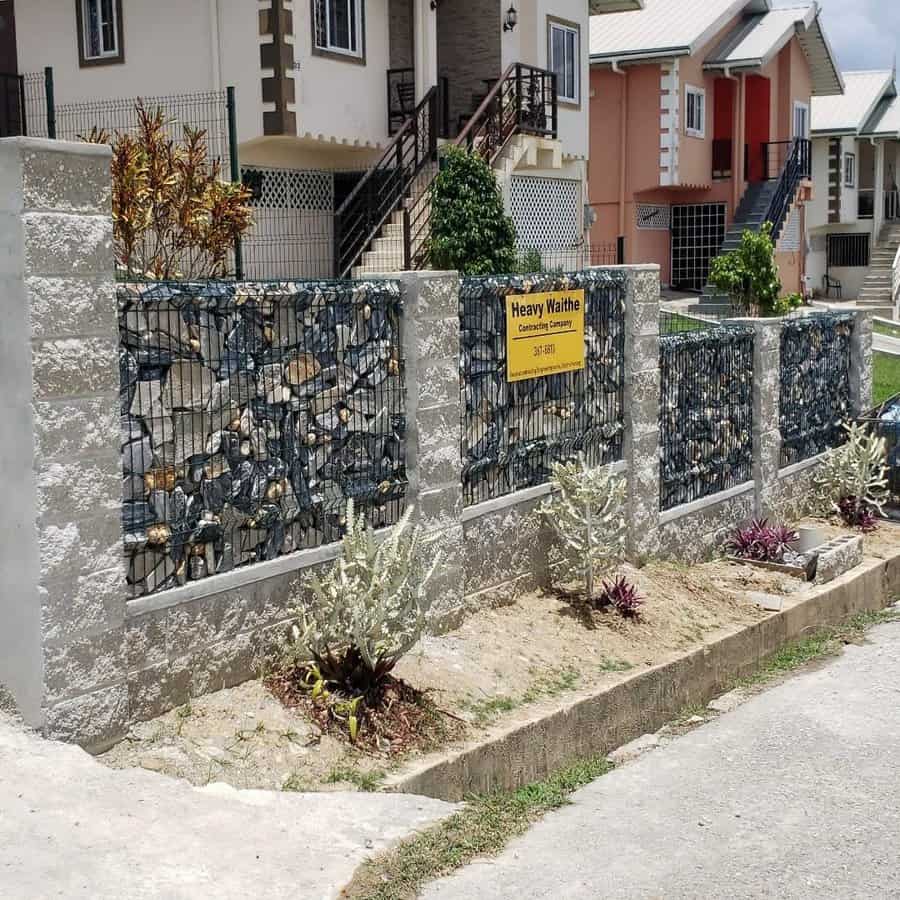 Gabion wall with signage in front of homes