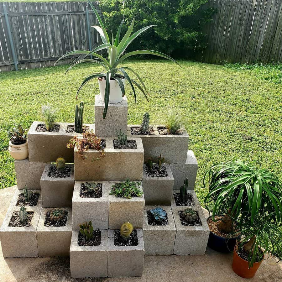 Tiered DIY cinder block planter filled with succulents, cacti, and greenery, creating a stylish and space-saving vertical garden in a backyard setting