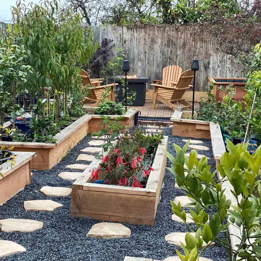 Charming garden with raised wooden planters, stone pathway, Adirondack chairs, and a cozy fire pit on a wooden deck