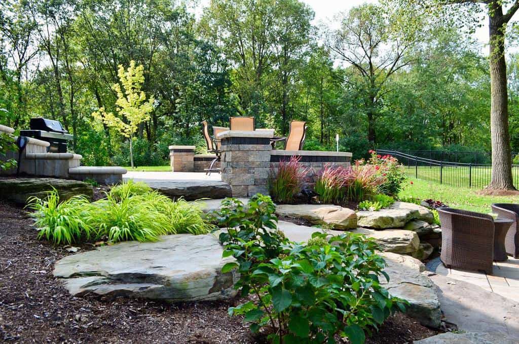 Outdoor patio with stone fire pit and seating in greenery