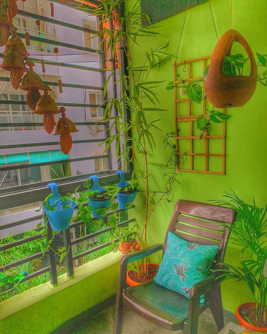 Vibrant green balcony with potted plants, hanging planters, bamboo decor, wind chimes, and a cozy chair with a blue cushion