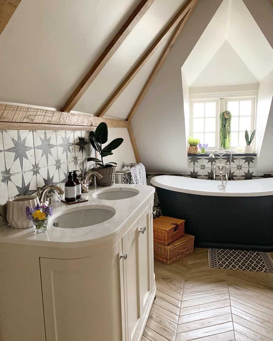 Charming attic bathroom with star-patterned tile backsplash, freestanding tub, double vanity, and cozy wood-beam ceiling.