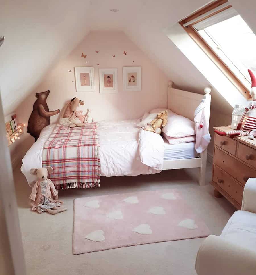 Whimsical attic bedroom with soft pink tones, plush toys, and cozy bedding. Skylights and fairy lights create a dreamy, charming retreat.