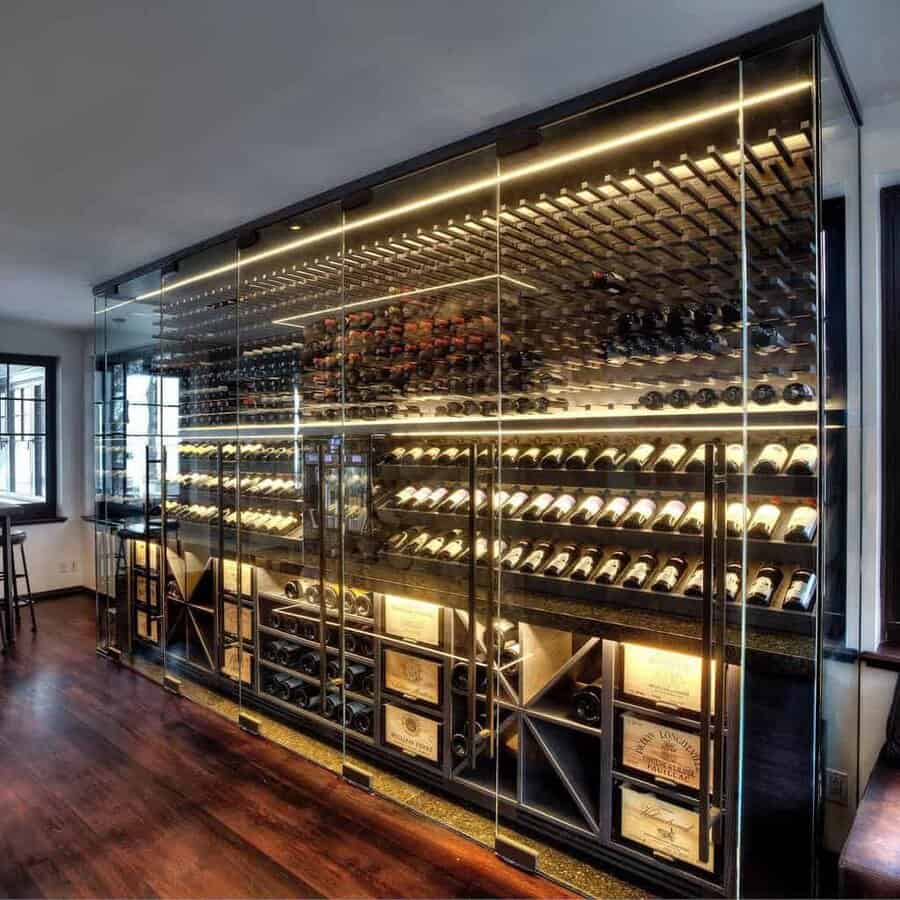 A contemporary wine cellar with glass walls, featuring a variety of wine bottles neatly arranged on racks and shelves