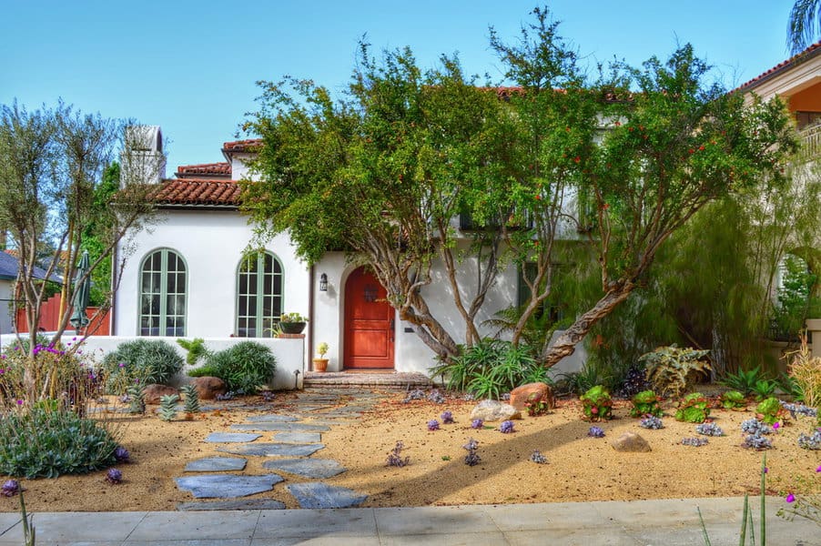 Spanish style home with desert landscaping and stone path