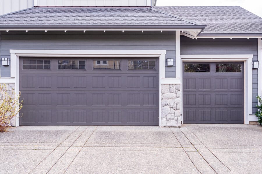 Home with double gray garage doors and stone pillar