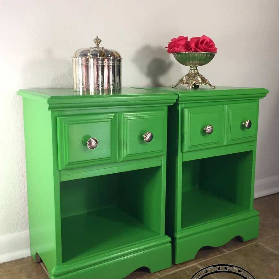 Vibrant green nightstands with silver knobs, styled with vintage silver decor and a floral arrangement for a bold, eclectic look.