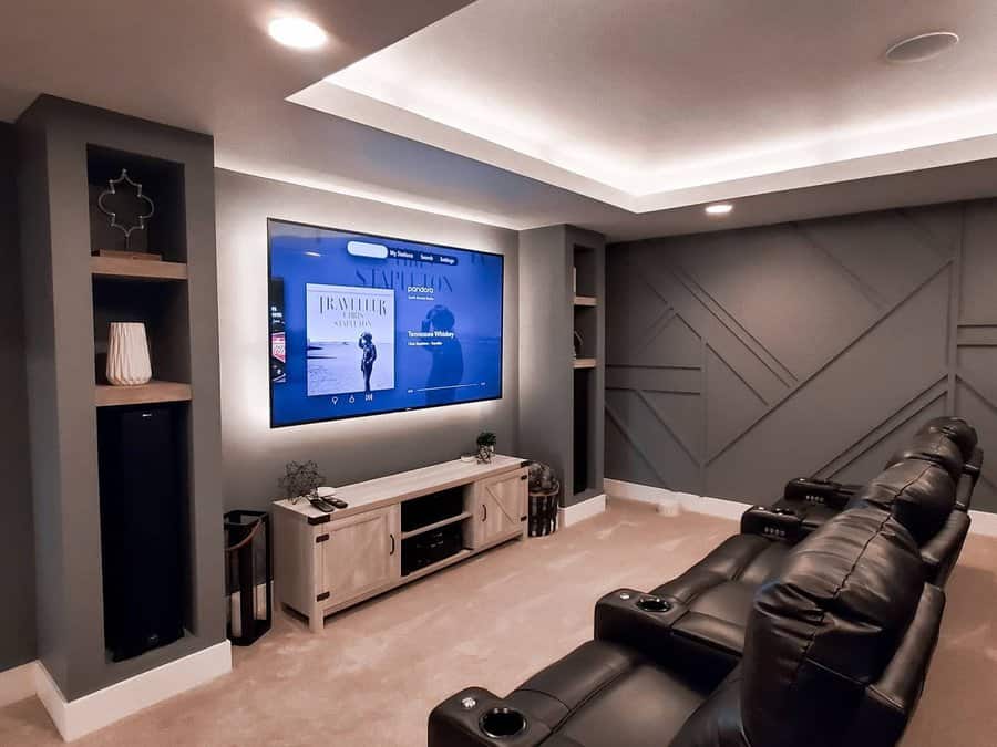 Sleek basement home theater with dark grey accent walls, recessed lighting, leather recliners, and built-in shelving for a cinematic experience.