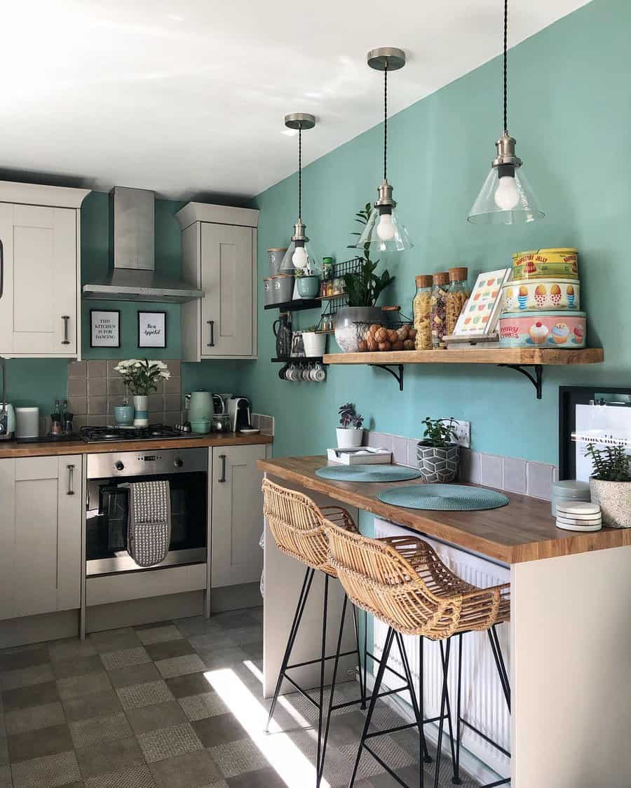 Checkered grey tile flooring adds character to this cozy kitchen, complementing soft cabinetry, wooden accents, and vibrant teal walls