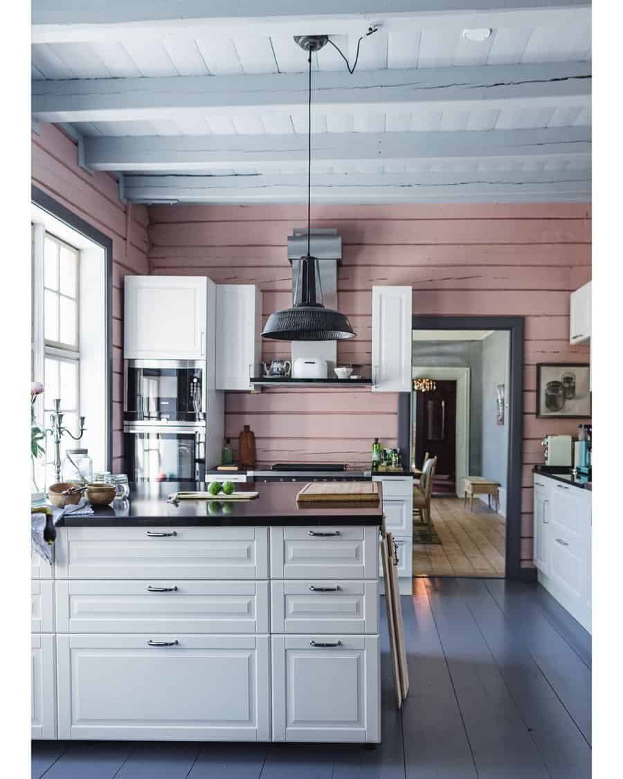 Soft grey wooden flooring complements this rustic kitchen, blending beautifully with pastel walls, white cabinetry, and a cozy farmhouse aesthetic