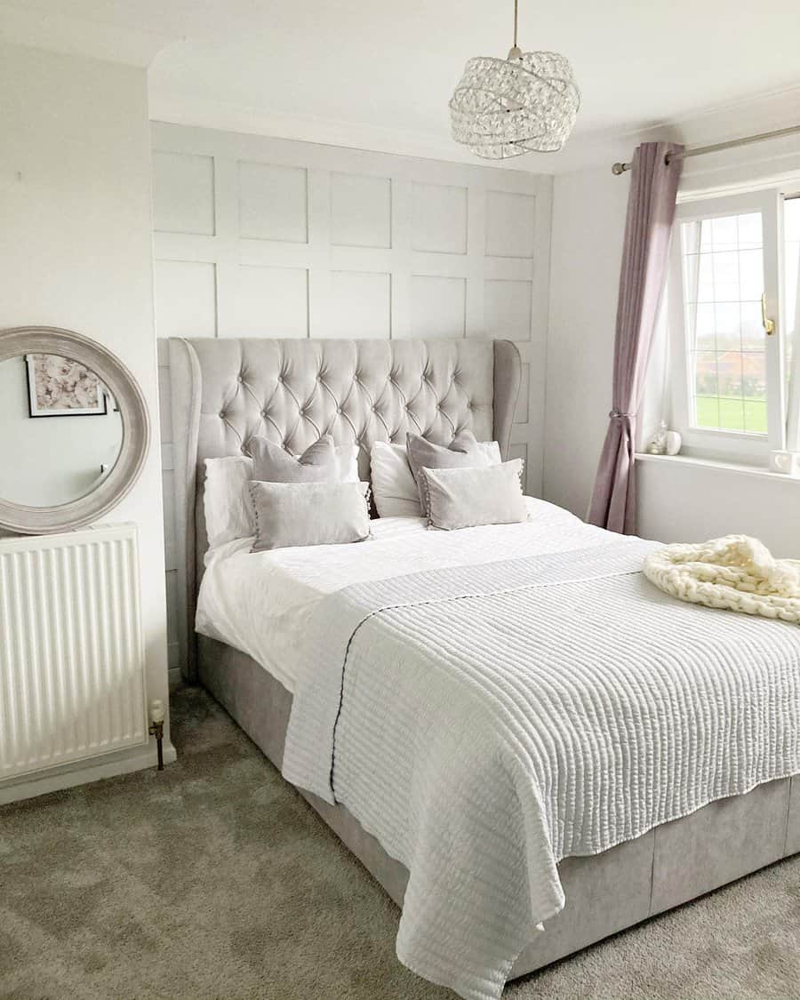 Chic grey bedroom with tufted headboard and chandelier