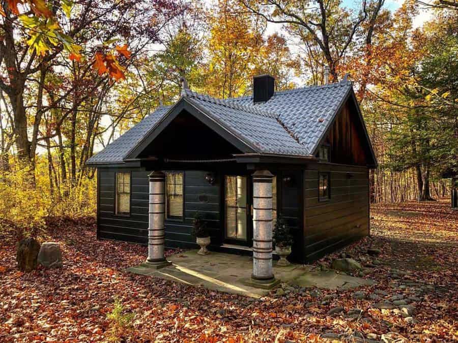 Small dark cabin with stone columns in a forest