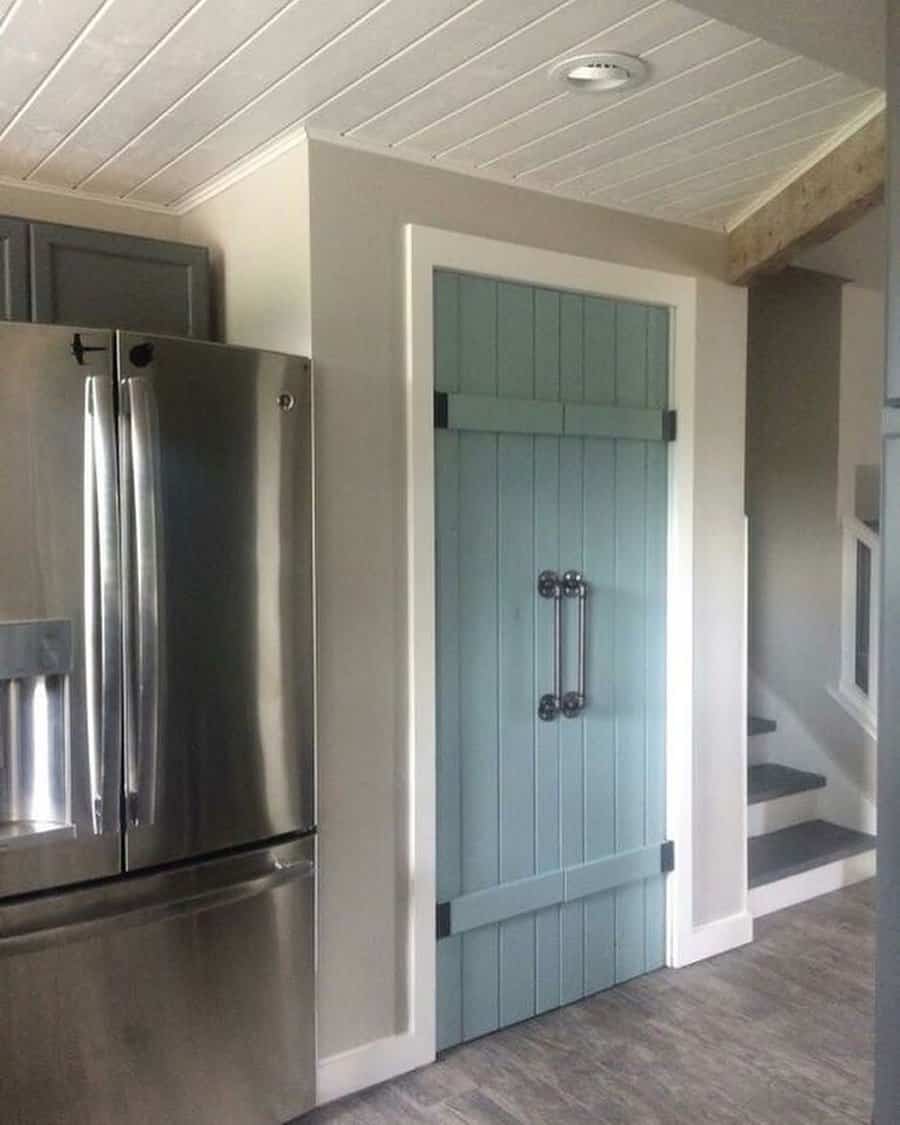 A charming blue barn-style closet door with black hardware and vintage handles adds a rustic touch to this modern farmhouse kitchen