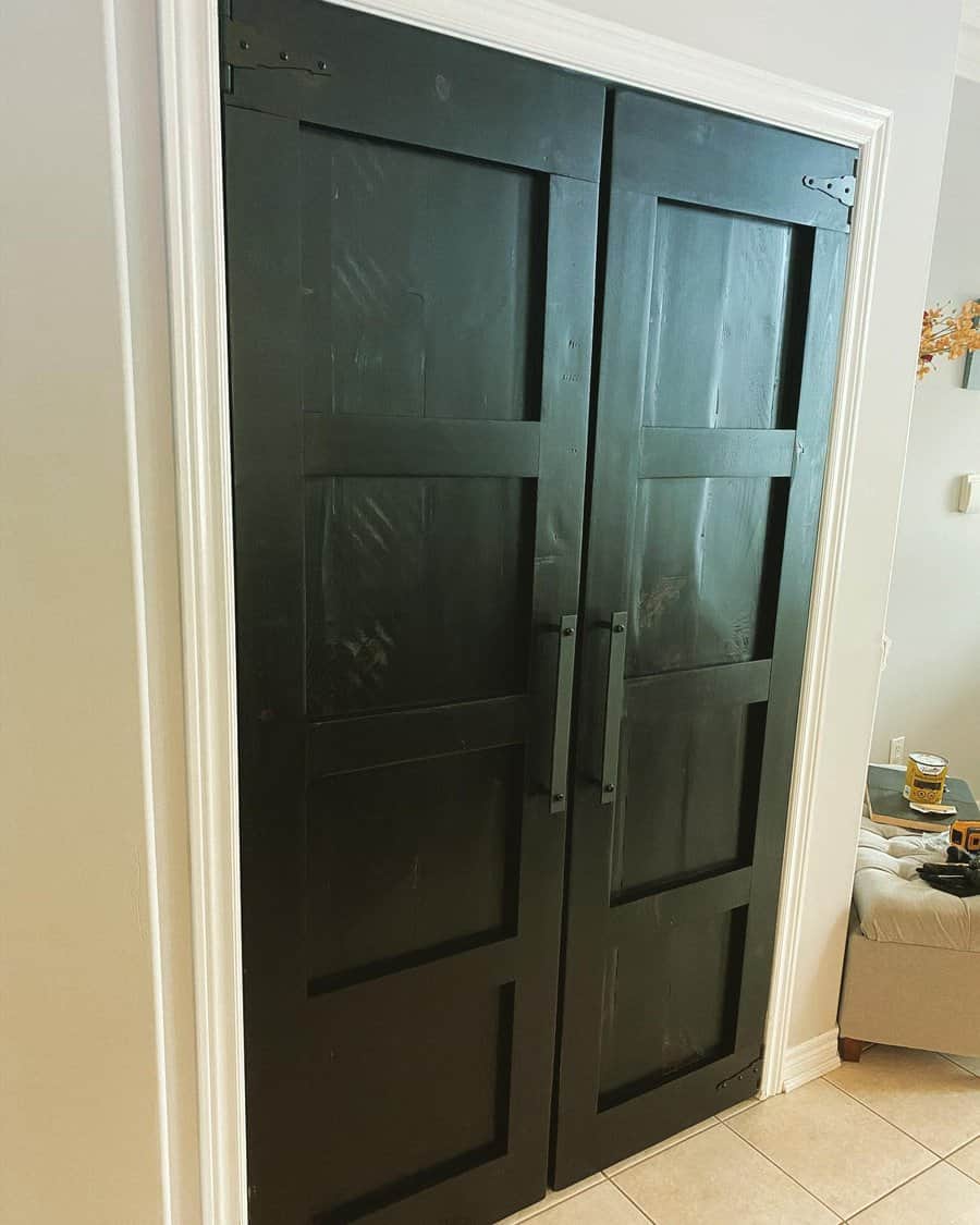 Bold black wooden double doors with rustic hardware create a striking statement, adding depth and contrast to this modern hallway space