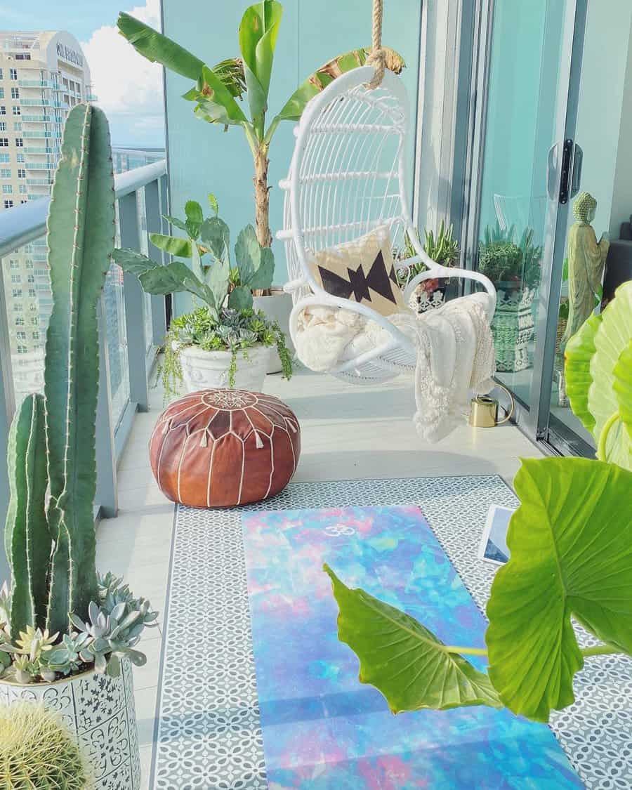 Bright and airy balcony with a white hanging chair, yoga mat, tropical plants, and a brown leather pouf, offering a serene high-rise view