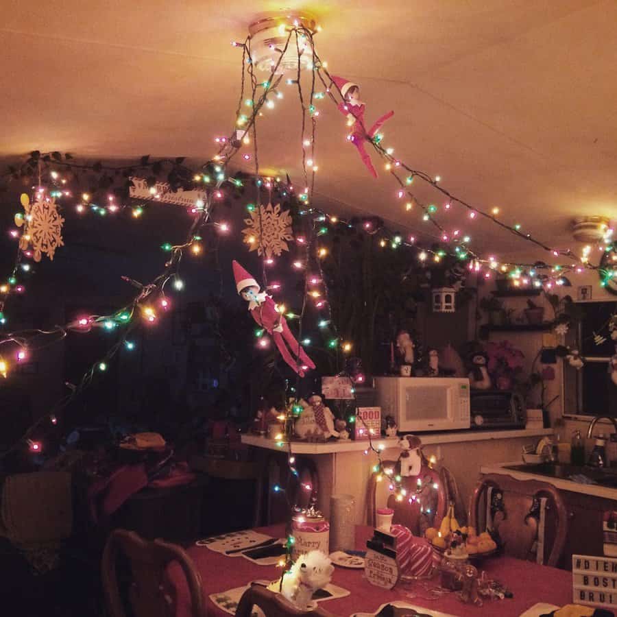 Room decorated with colorful string lights, snowflake ornaments, and toy elves hanging from the ceiling