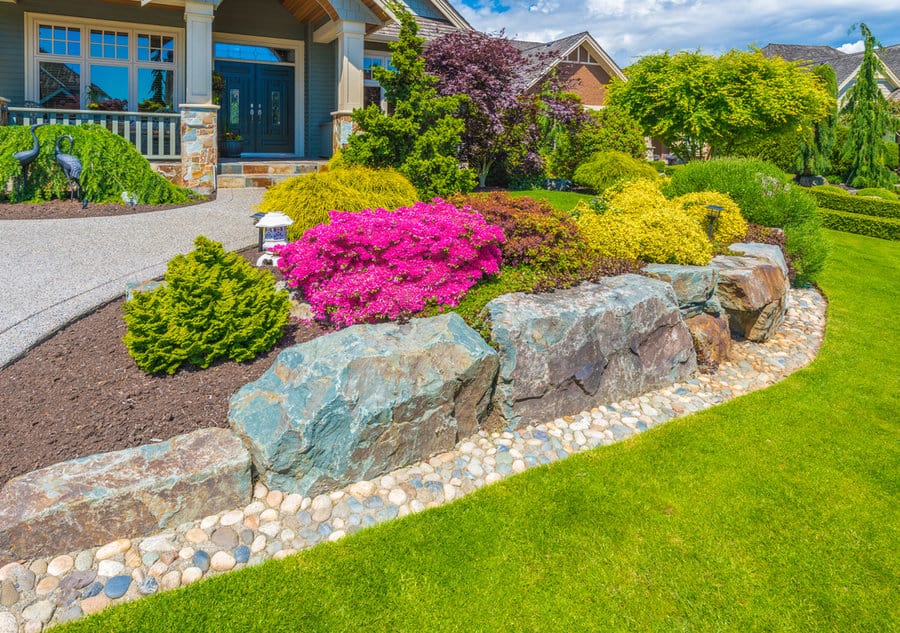 House with colorful shrubs and stone retaining wall