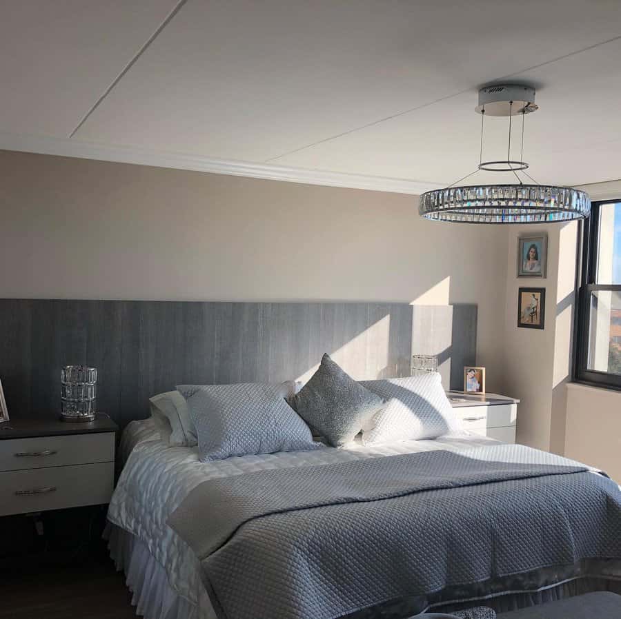 Sunlit bedroom with modern chandelier and patterned bedding