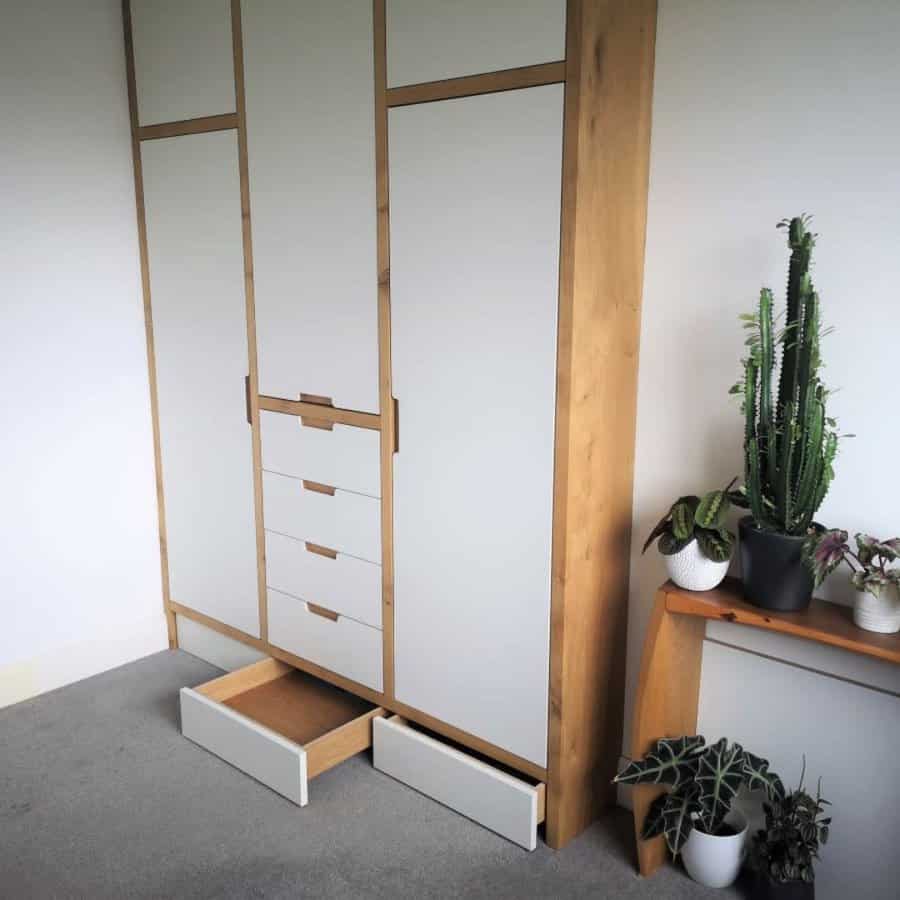 A modern wardrobe with hidden under-cabinet drawers, sleek white and wood finishes, and built-in storage for a minimalist and functional design