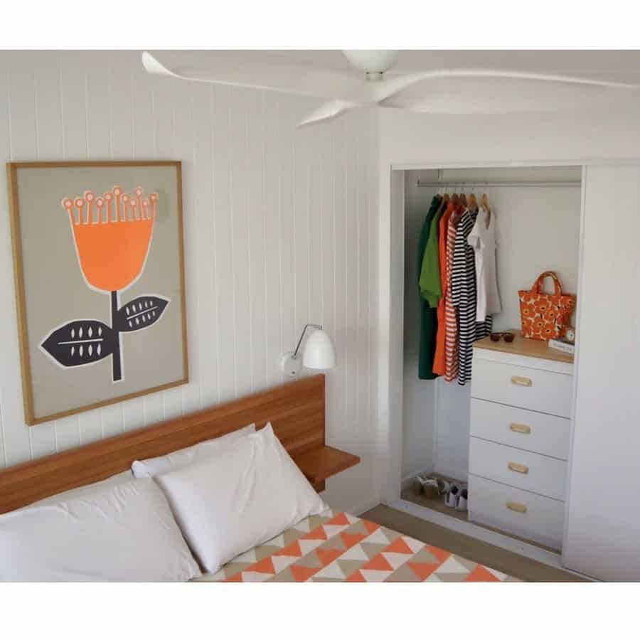 A modern bedroom with a built-in closet featuring a dresser, hanging space, and a sliding door for a clean and organized small-space solution