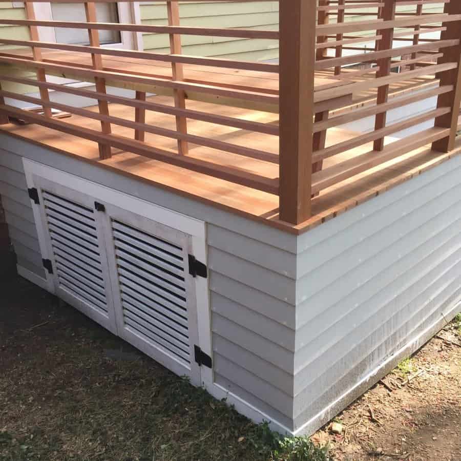 Deck with white louvered skirting and wooden railing