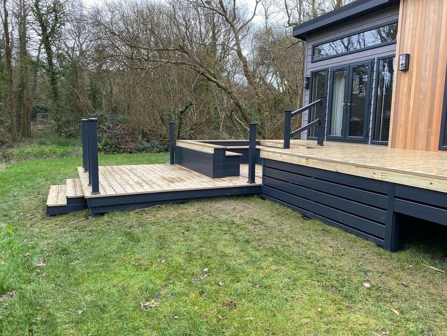 Modern deck with black horizontal skirting by forest