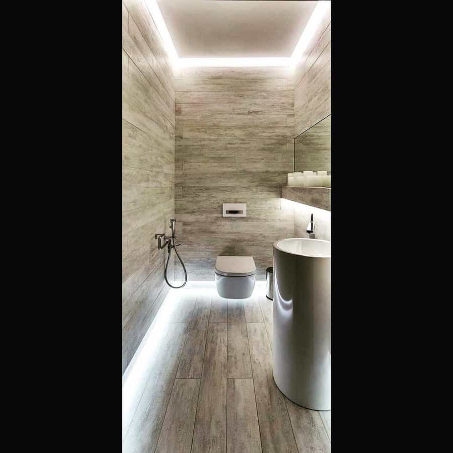 Minimalist bathroom with a floating ceiling, hidden LED lighting, and wood-textured walls, creating a sleek and futuristic ambiance.