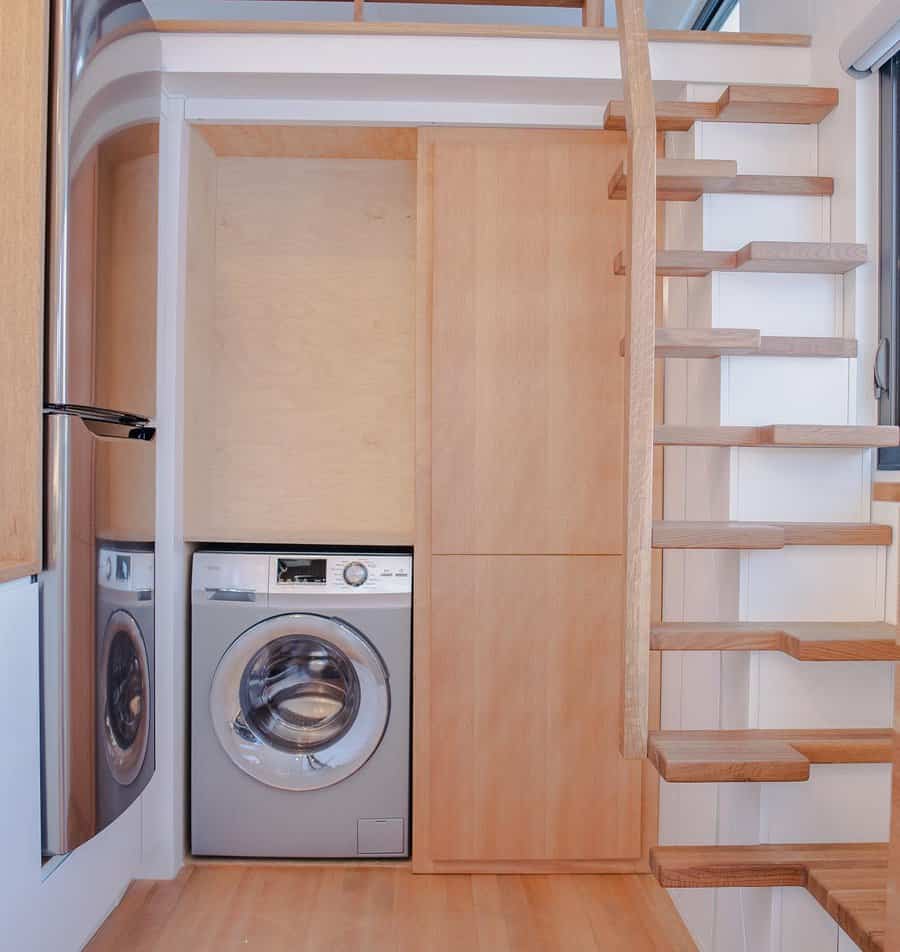 Tiny home interior with washing machine and wooden stairs