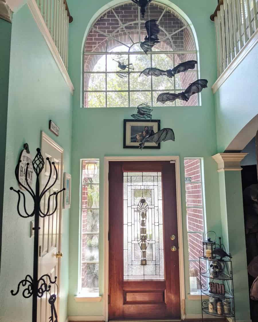 Decorated entryway with bat decorations hanging from ceiling above a wooden front door