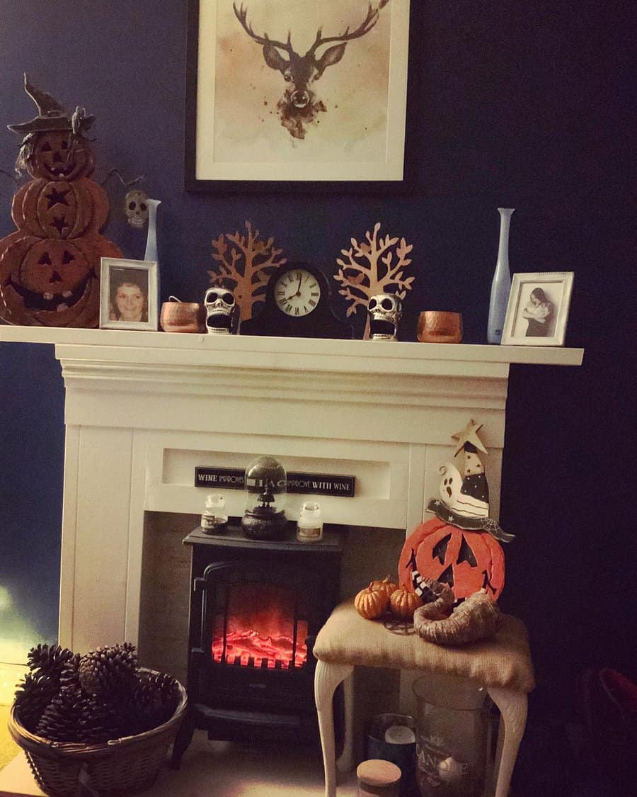 Halloween-themed decorations on a mantel and stool in front of a white fireplace