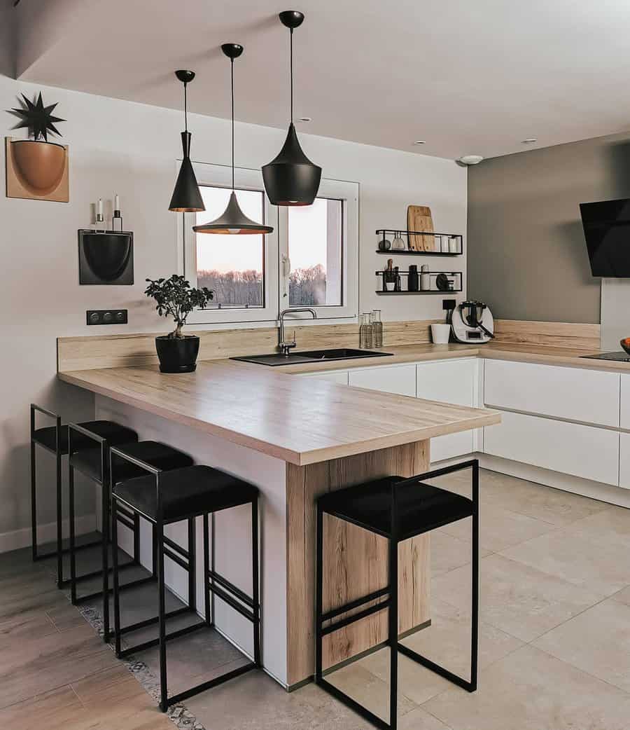 Minimalist industrial kitchen with a wood and white breakfast bar, sleek black barstools, modern pendant lighting, and stylish open shelving