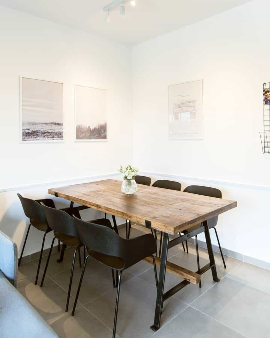 Minimalist dining area with a wooden table, six black chairs, and wall art featuring a white vase with flowers on the table