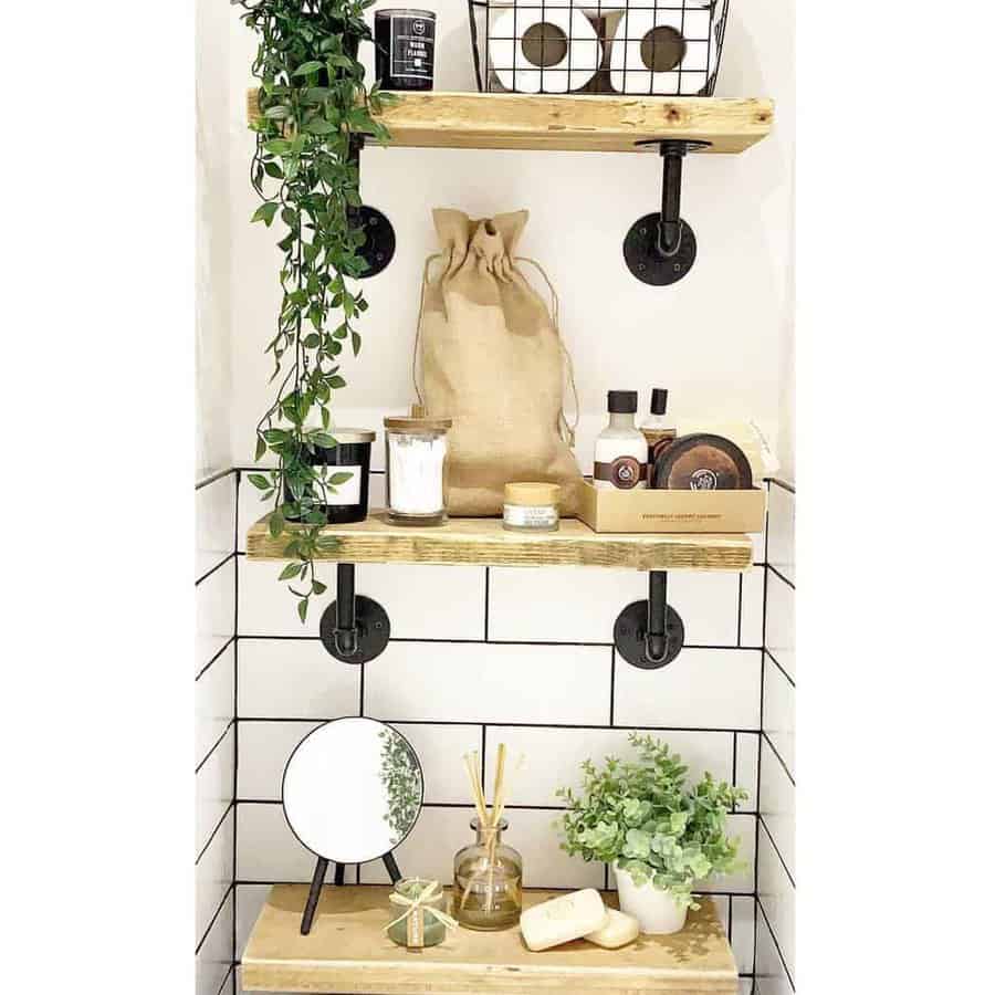 Bathroom shelves with potted plants, candles, a mirror, and toiletries, against a white tiled wall