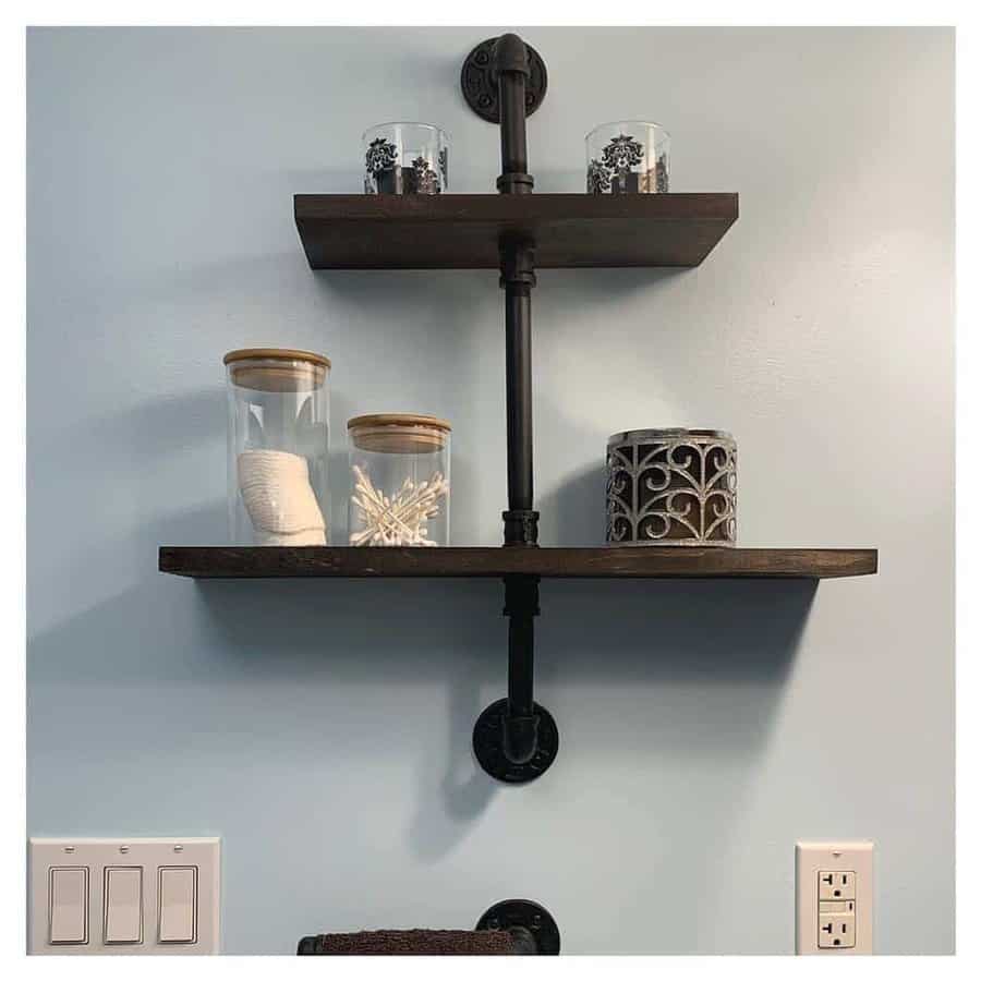 Wall shelves with jars and decor items, featuring an industrial pipe design against a light blue wall