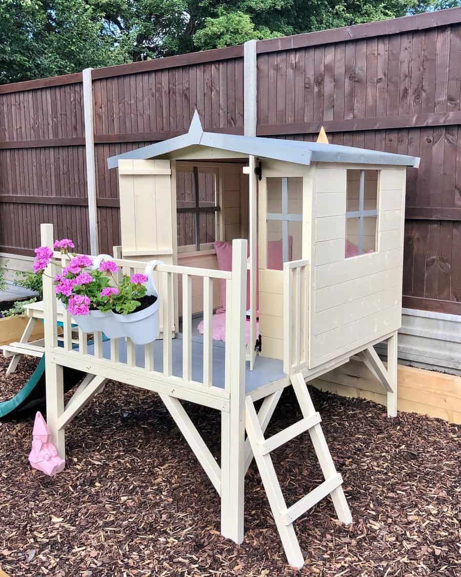 Elevated wooden playhouse with flower pot and pink accents