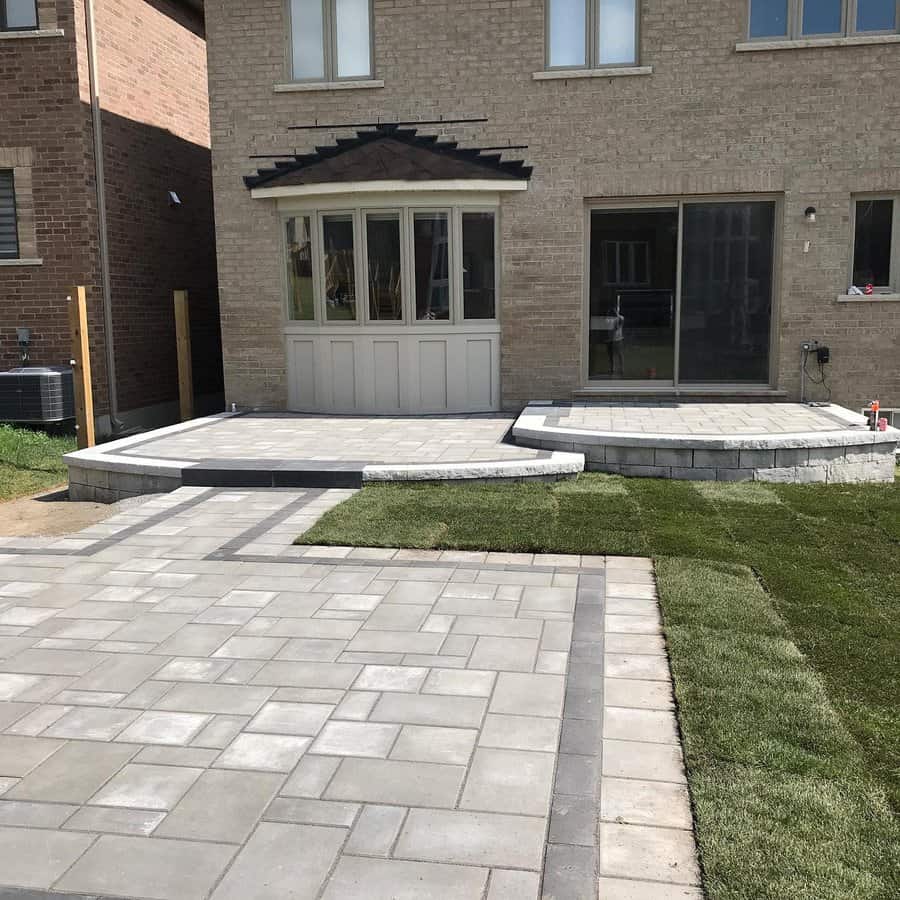 Raised brick patio with steps in a suburban backyard