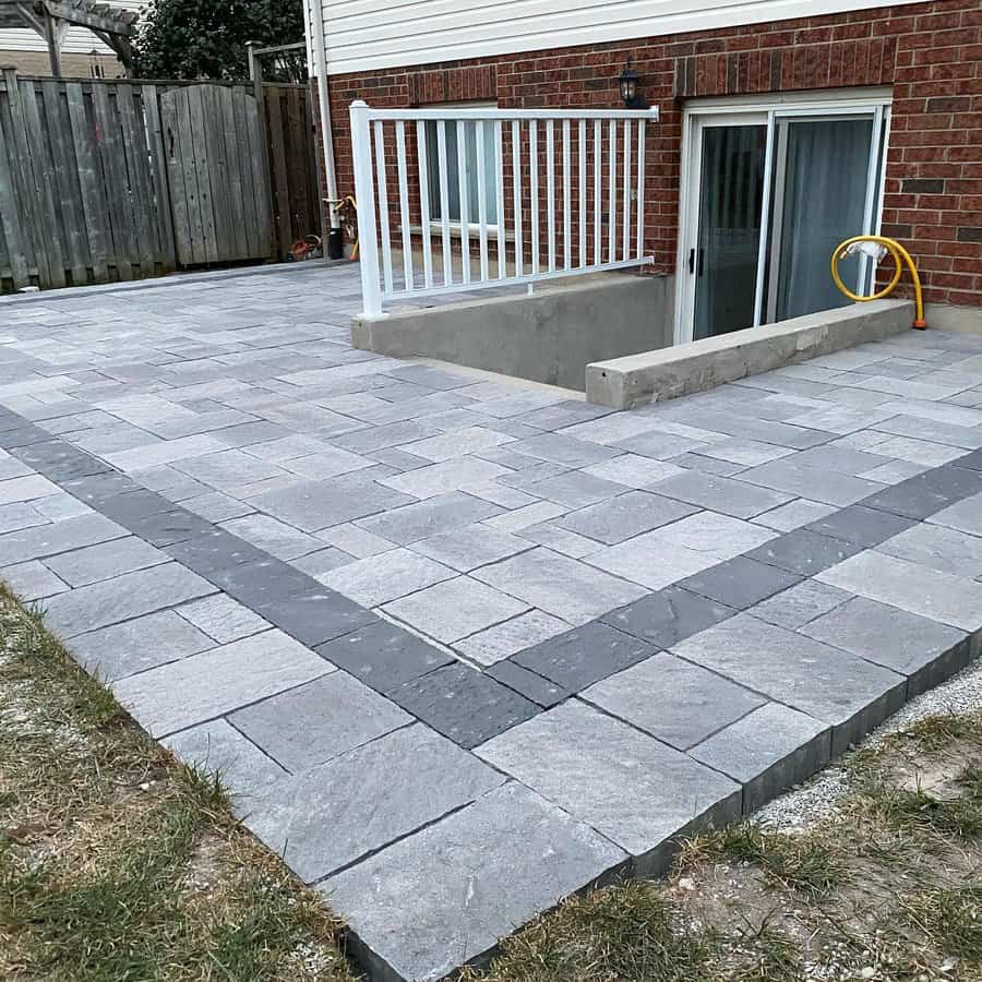 Gray interlocking brick patio with white railing and steps