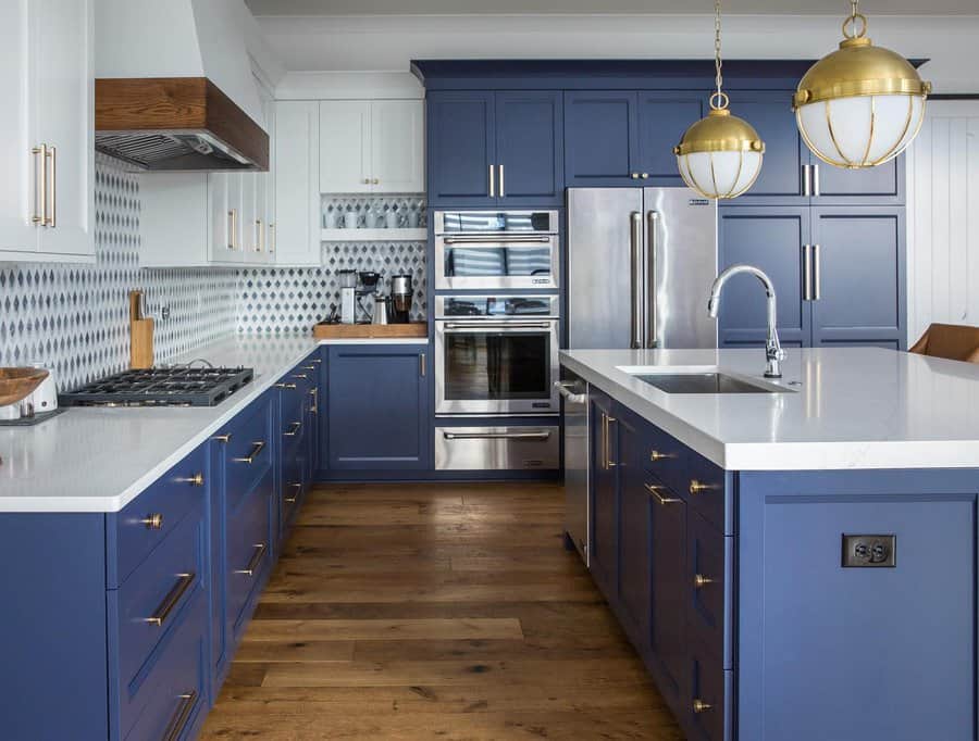 Elegant kitchen with navy blue cabinets, gold accents, a sleek island sink, quartz countertops, and statement pendant lighting for a modern touch