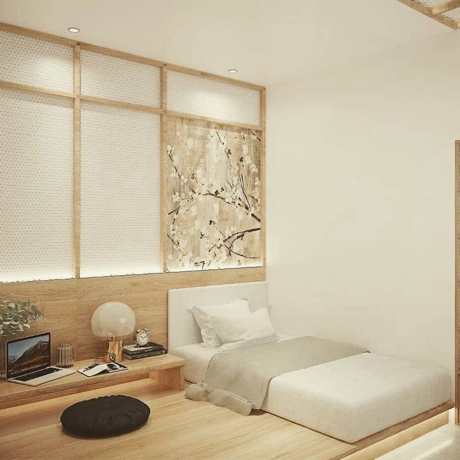 Minimalist bedroom with a low bed, wooden accents, wall art, and a small desk with a laptop; soft lighting and neutral tones