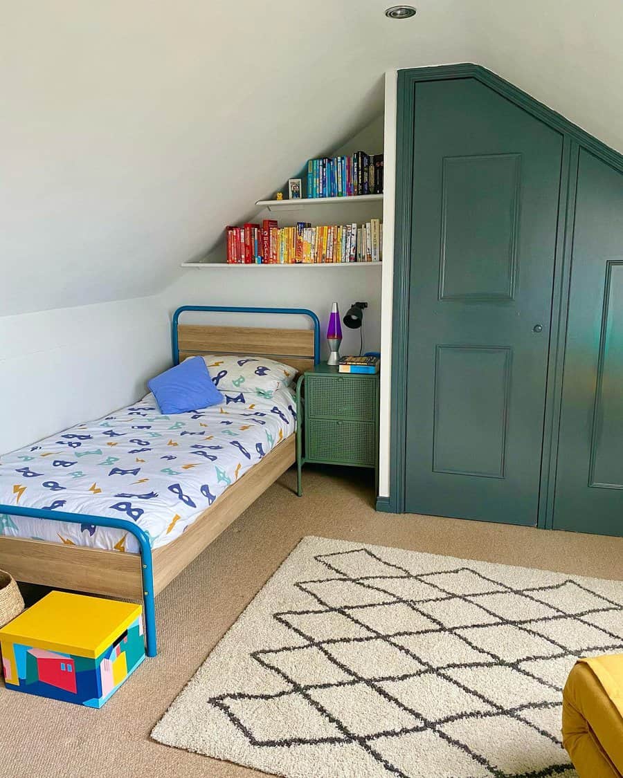 Playful attic kids' bedroom with a blue metal bed, built-in storage, and colorful decor. A cozy reading nook and bold green closet add charm.